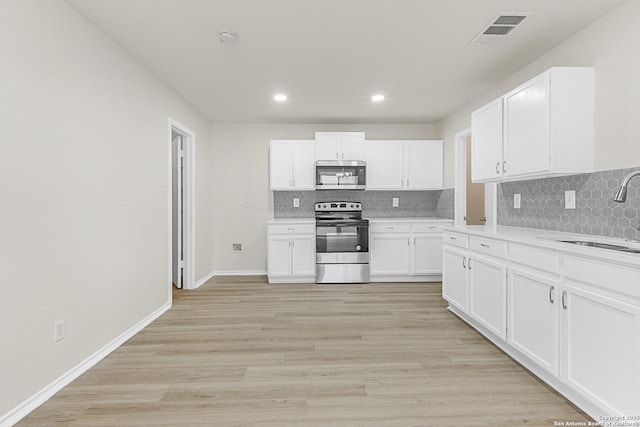 kitchen with white cabinetry, sink, stainless steel appliances, and light wood-type flooring