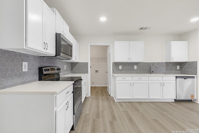 kitchen with white cabinetry, sink, light wood-type flooring, and appliances with stainless steel finishes