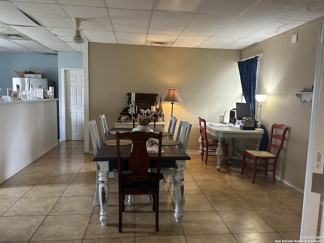 tiled dining space with a paneled ceiling