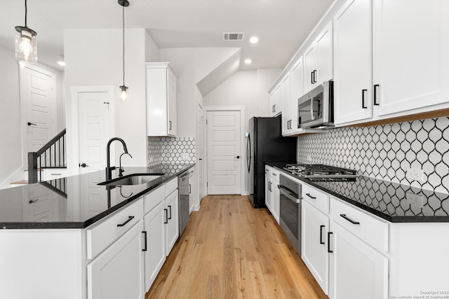 kitchen with pendant lighting, sink, white cabinets, stainless steel appliances, and light wood-type flooring