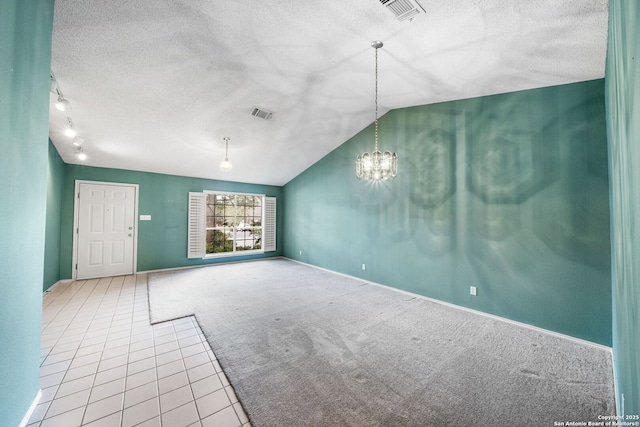 carpeted empty room with lofted ceiling, an inviting chandelier, track lighting, and a textured ceiling