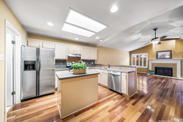 kitchen with stainless steel appliances, white cabinetry, a kitchen island, and kitchen peninsula