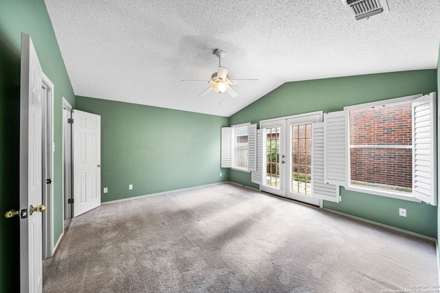 carpeted spare room with french doors, ceiling fan, lofted ceiling, and a textured ceiling