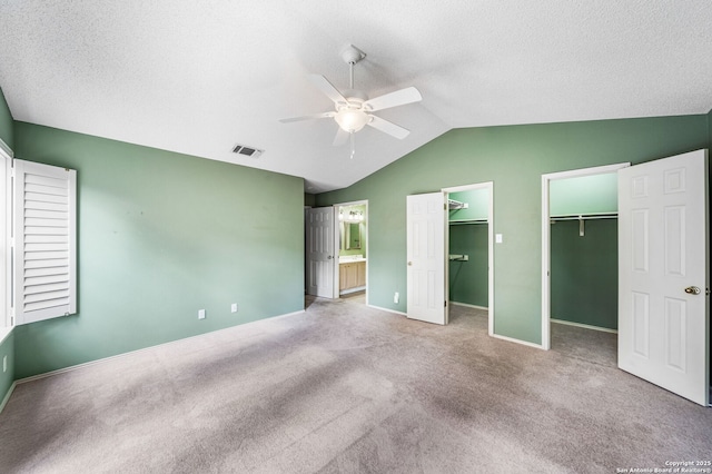 unfurnished bedroom with vaulted ceiling, carpet floors, ceiling fan, and a textured ceiling