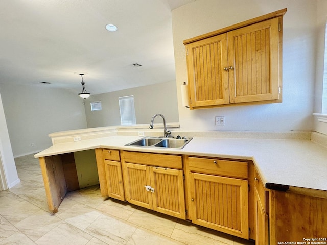 kitchen featuring decorative light fixtures, kitchen peninsula, and sink