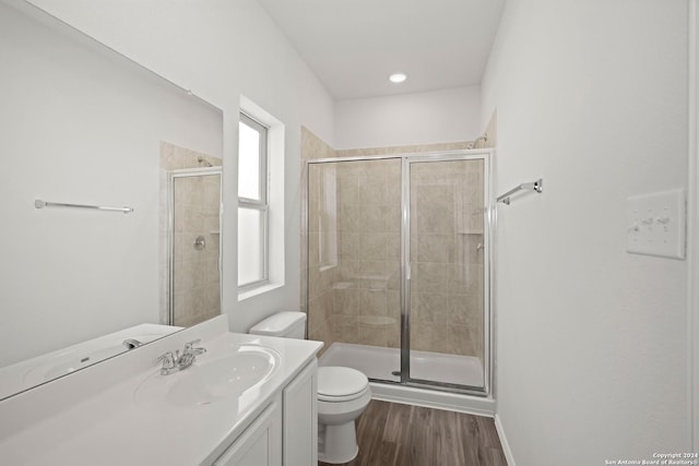 bathroom with vanity, hardwood / wood-style floors, a shower with door, and toilet