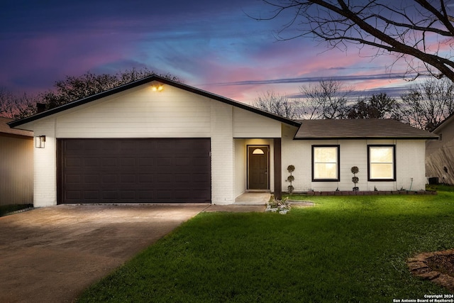 single story home featuring a garage and a lawn