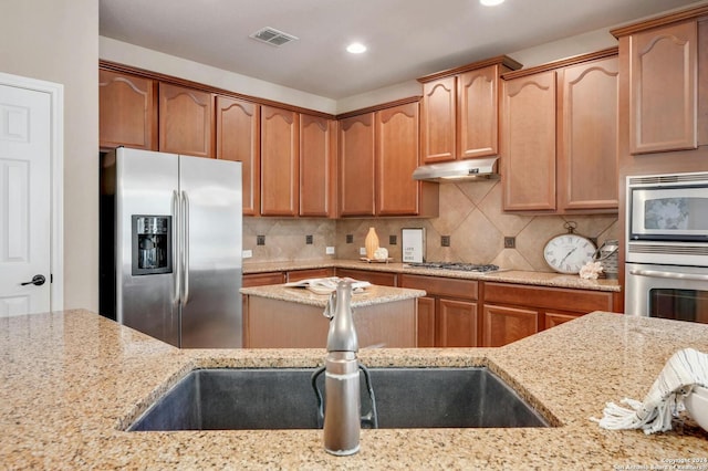 kitchen with decorative backsplash, light stone countertops, and appliances with stainless steel finishes