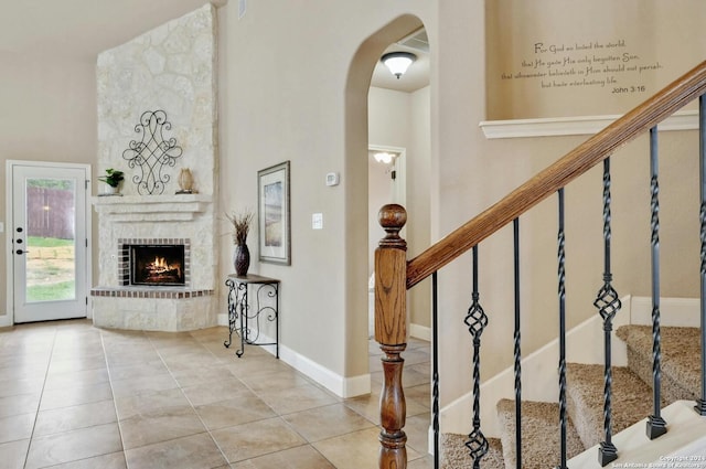 interior space with tile patterned flooring, a brick fireplace, and a high ceiling