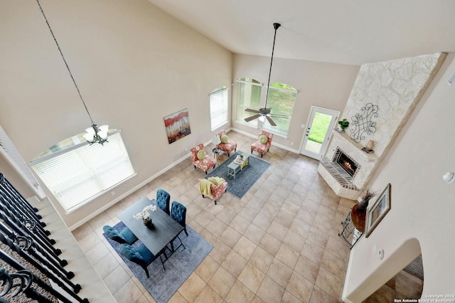 living room with light tile patterned flooring, ceiling fan, high vaulted ceiling, and a brick fireplace