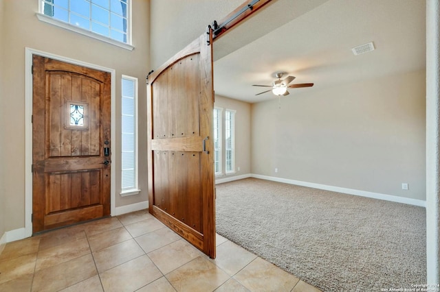 carpeted entrance foyer featuring ceiling fan and a barn door