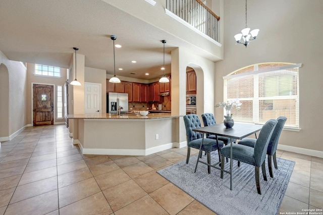 tiled dining space featuring an inviting chandelier, sink, and a high ceiling