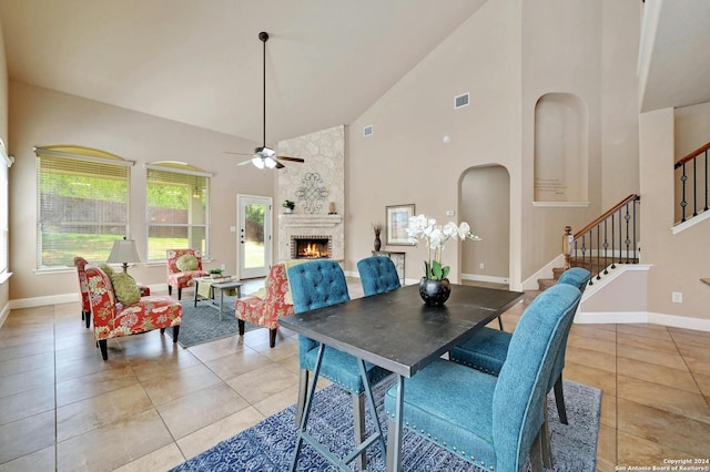 dining space featuring ceiling fan, high vaulted ceiling, light tile patterned floors, and a fireplace