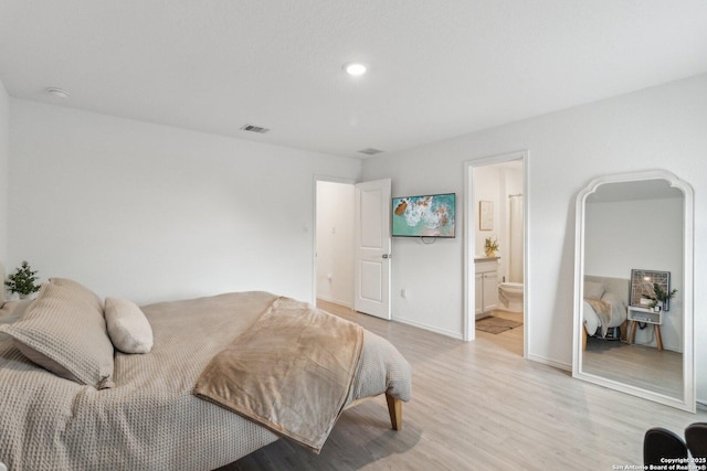 bedroom featuring ensuite bath and light hardwood / wood-style floors