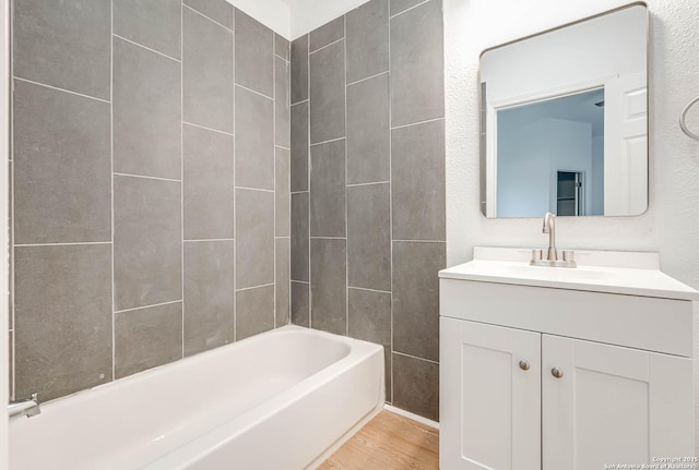 bathroom featuring hardwood / wood-style flooring, vanity, and tiled shower / bath combo