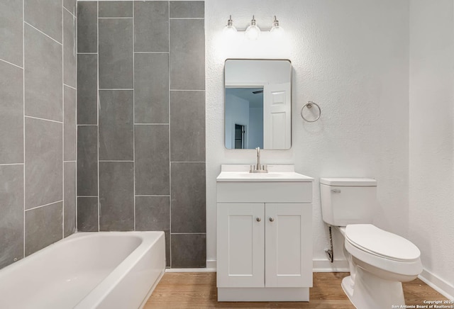 full bathroom featuring vanity, tiled shower / bath, wood-type flooring, and toilet