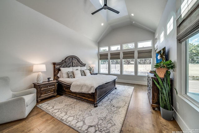 bedroom featuring ceiling fan, high vaulted ceiling, multiple windows, and light wood-type flooring