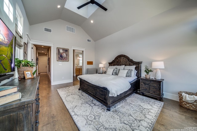 bedroom with wood-type flooring, ensuite bath, high vaulted ceiling, and a skylight