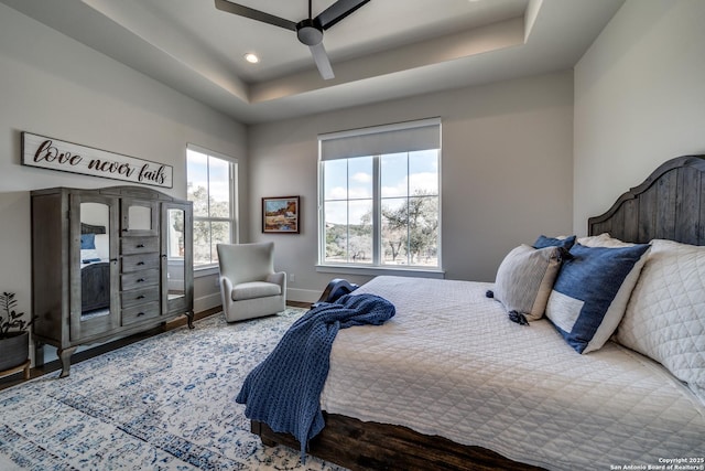 bedroom with hardwood / wood-style floors, a raised ceiling, and ceiling fan