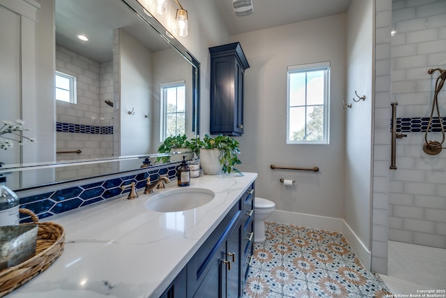 bathroom with tiled shower, vanity, and toilet