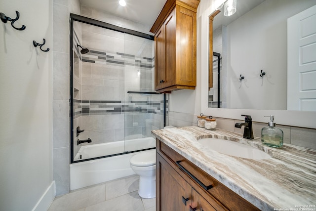 full bathroom with tile patterned flooring, bath / shower combo with glass door, vanity, and toilet