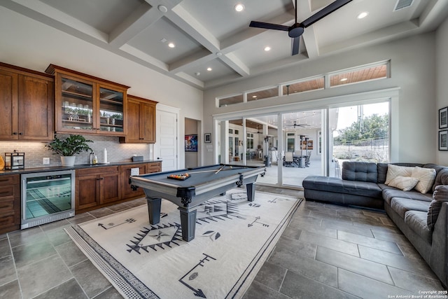 game room featuring ceiling fan, bar, beverage cooler, and a towering ceiling