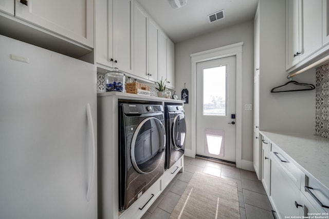 laundry area featuring cabinets, washing machine and dryer, and tile patterned floors