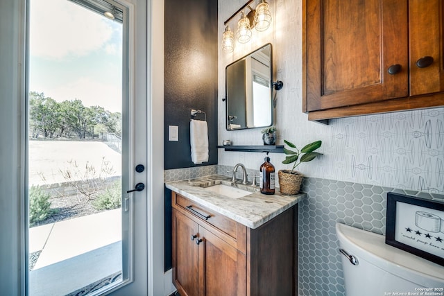 bathroom featuring vanity, decorative backsplash, and toilet