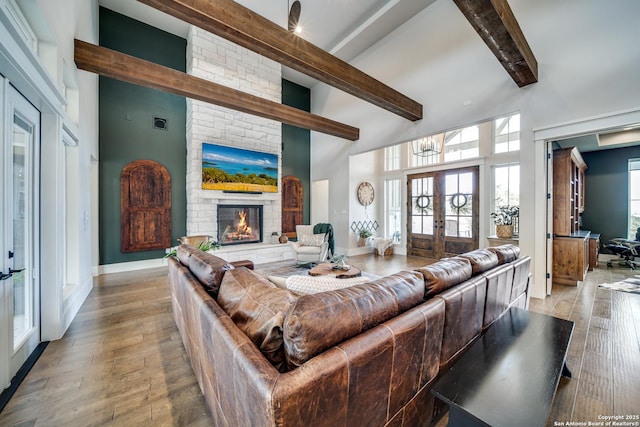 living room with french doors, high vaulted ceiling, light hardwood / wood-style flooring, beamed ceiling, and a fireplace