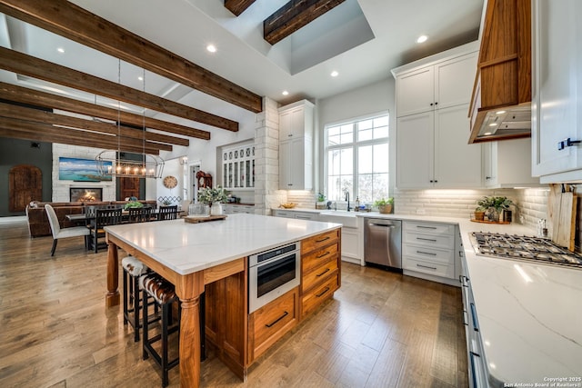 kitchen featuring stainless steel appliances, light stone counters, tasteful backsplash, white cabinets, and a kitchen island