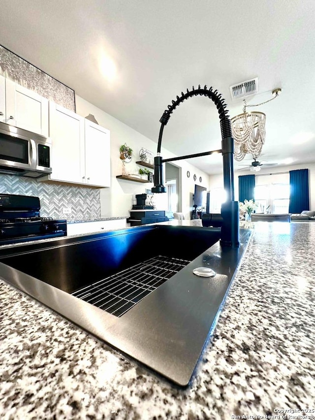 kitchen with white cabinetry, ceiling fan, black range with gas stovetop, and tasteful backsplash