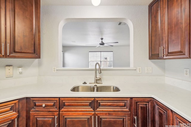 kitchen with sink, light stone countertops, and ceiling fan