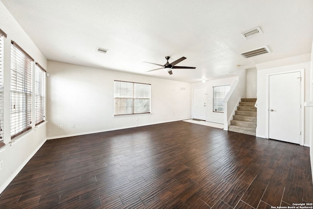 unfurnished living room featuring dark wood-type flooring, ceiling fan, and plenty of natural light