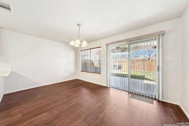 unfurnished dining area featuring dark hardwood / wood-style flooring and an inviting chandelier