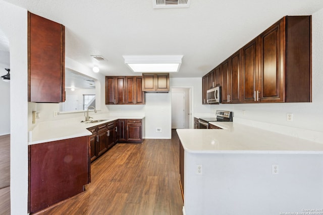 kitchen with sink, dark wood-type flooring, stainless steel appliances, and kitchen peninsula