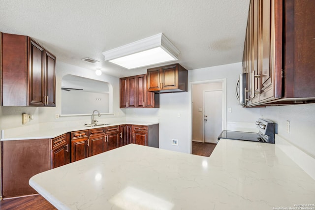 kitchen with sink, range, a textured ceiling, and kitchen peninsula