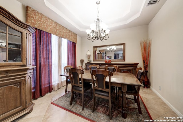 dining area featuring a raised ceiling, light tile patterned floors, and a notable chandelier