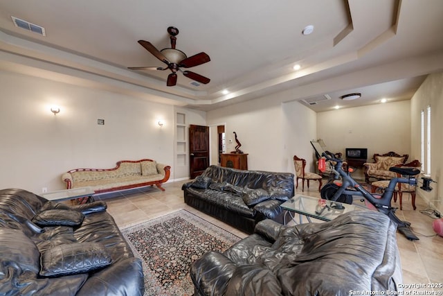 tiled living room featuring ceiling fan and a tray ceiling