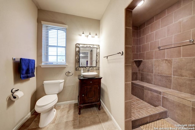 bathroom with vanity, tile patterned floors, toilet, and tiled shower