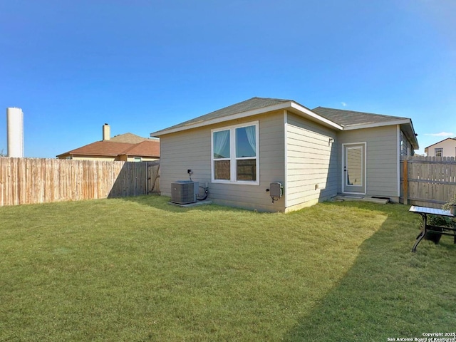 back of house with central AC unit and a yard