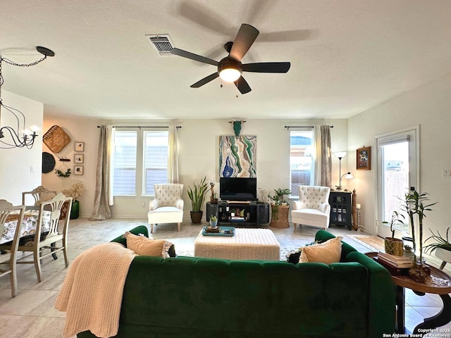 living room with ceiling fan with notable chandelier