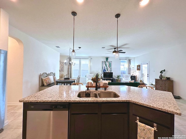 kitchen with light stone counters, light tile patterned floors, stainless steel dishwasher, ceiling fan, and a kitchen island with sink