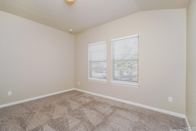 carpeted spare room featuring vaulted ceiling and a textured ceiling