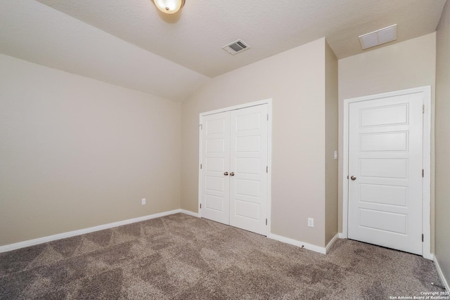 unfurnished bedroom featuring vaulted ceiling, a closet, and carpet flooring