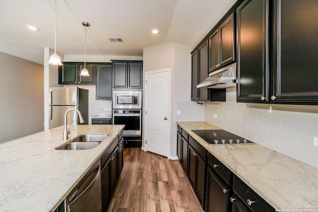 kitchen with pendant lighting, sink, appliances with stainless steel finishes, wood-type flooring, and light stone countertops