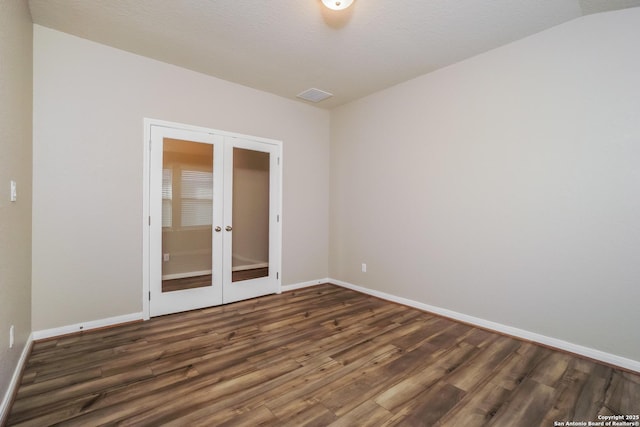 empty room featuring vaulted ceiling, dark hardwood / wood-style floors, a textured ceiling, and french doors