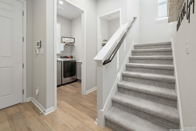 stairs with washer and dryer and hardwood / wood-style floors