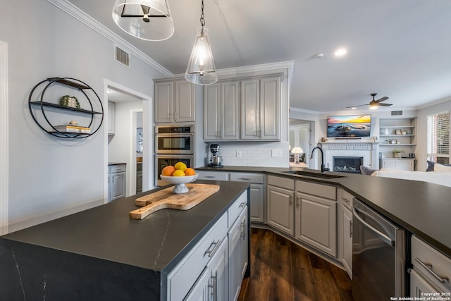 kitchen featuring sink, crown molding, appliances with stainless steel finishes, gray cabinets, and a kitchen island