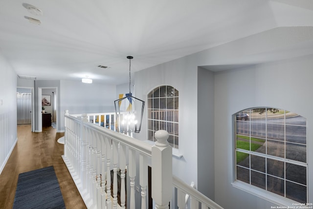 corridor with dark hardwood / wood-style floors and an inviting chandelier