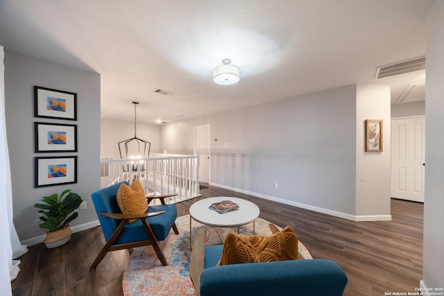 sitting room featuring a textured ceiling, a notable chandelier, and dark hardwood / wood-style flooring